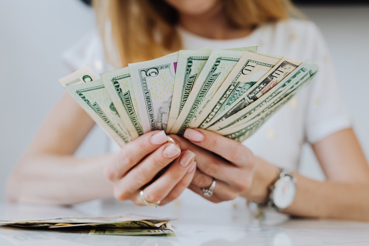 Close-up of a woman counting US dollar bills, symbolizing financial success and wealth management.